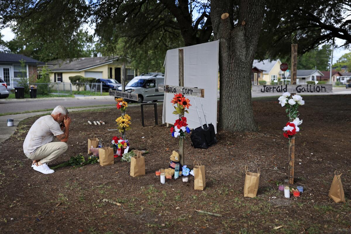 A mourner prays in front of crosses honoring the victims of the shooting at a Dollar General store in Jacksonville, Fla.