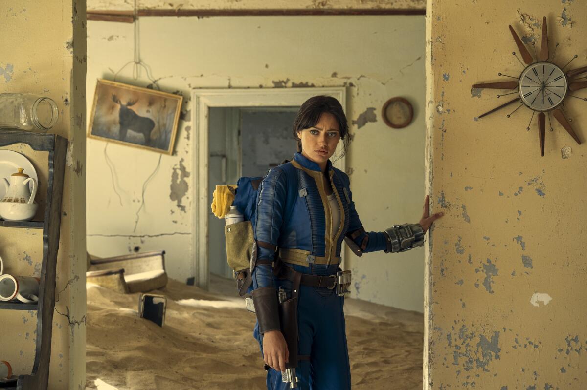 A woman stands in a doorway in a derelict building in "Fallout."