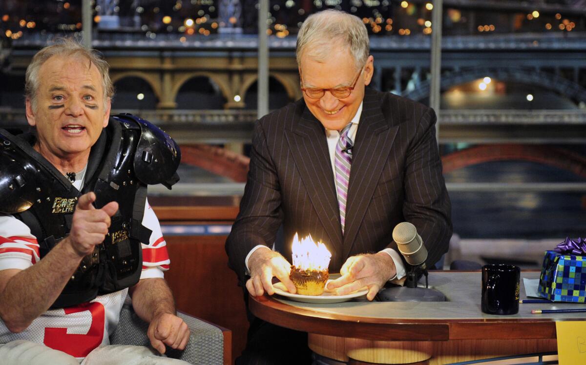 Bill Murray, left, tells the audience not to scream after lighting 30 birthday candles in a cupcake as a gift to host David Letterman for his 30 years in TV, on the set of the "Late Show with David Letterman" on Jan. 31, 2012.