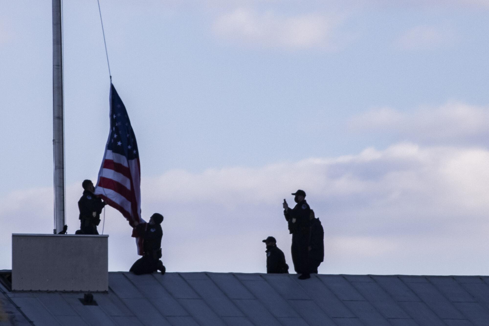 Capitol Police officers lower and replace the American flag to half staff over the U.S. Capitol