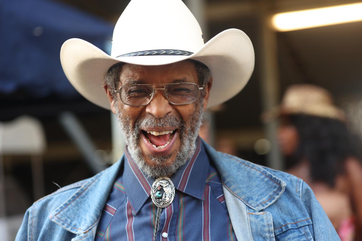 A man in a cowboy hat laughs.