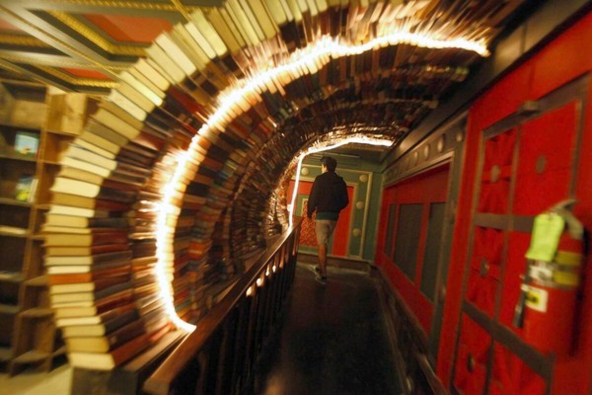 A man walks through an archway made of books in the Last Bookstore.