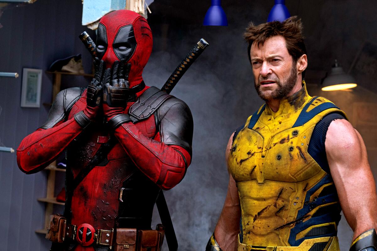Ryan Reynolds as Deadpool covers his mouth in shock next to Hugh Jackman as Wolverine.