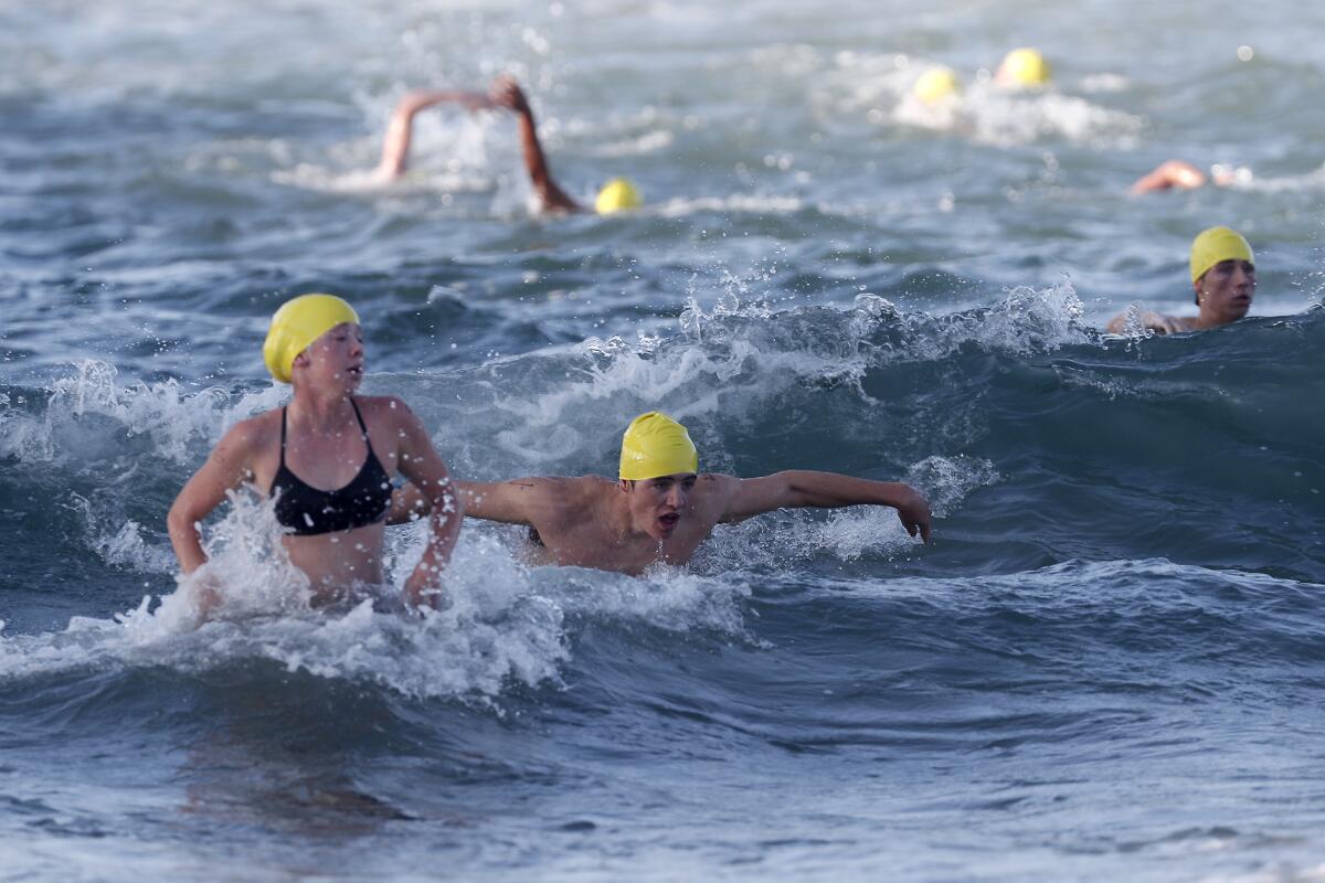 Participants race back to the beach as they compete in Huntington Beach's lifeguard tryouts.