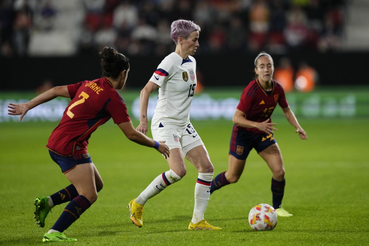 U.S. forward Megan Rapinoe, center, controls the ball between two Spain players.