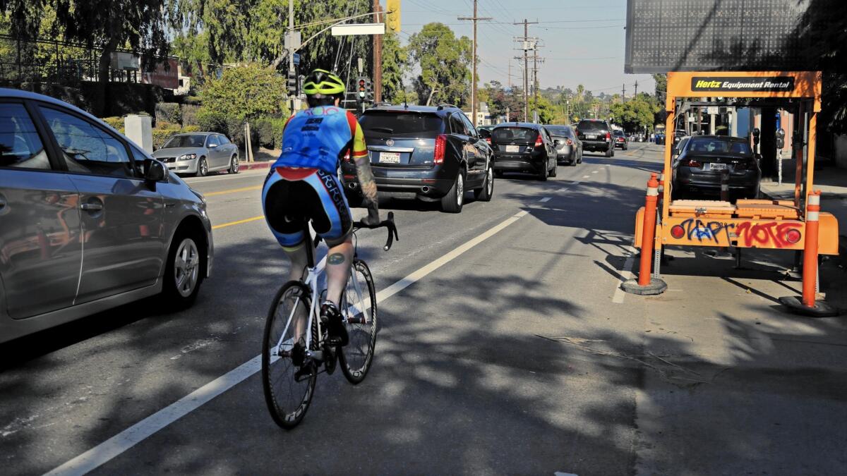 A cyclist rides alongside vehicle traffic on Rowena Avenue in Silver Lake. The city's Mobility Plan 2035 would add hundreds of miles of bicycle and bus-only lanes.