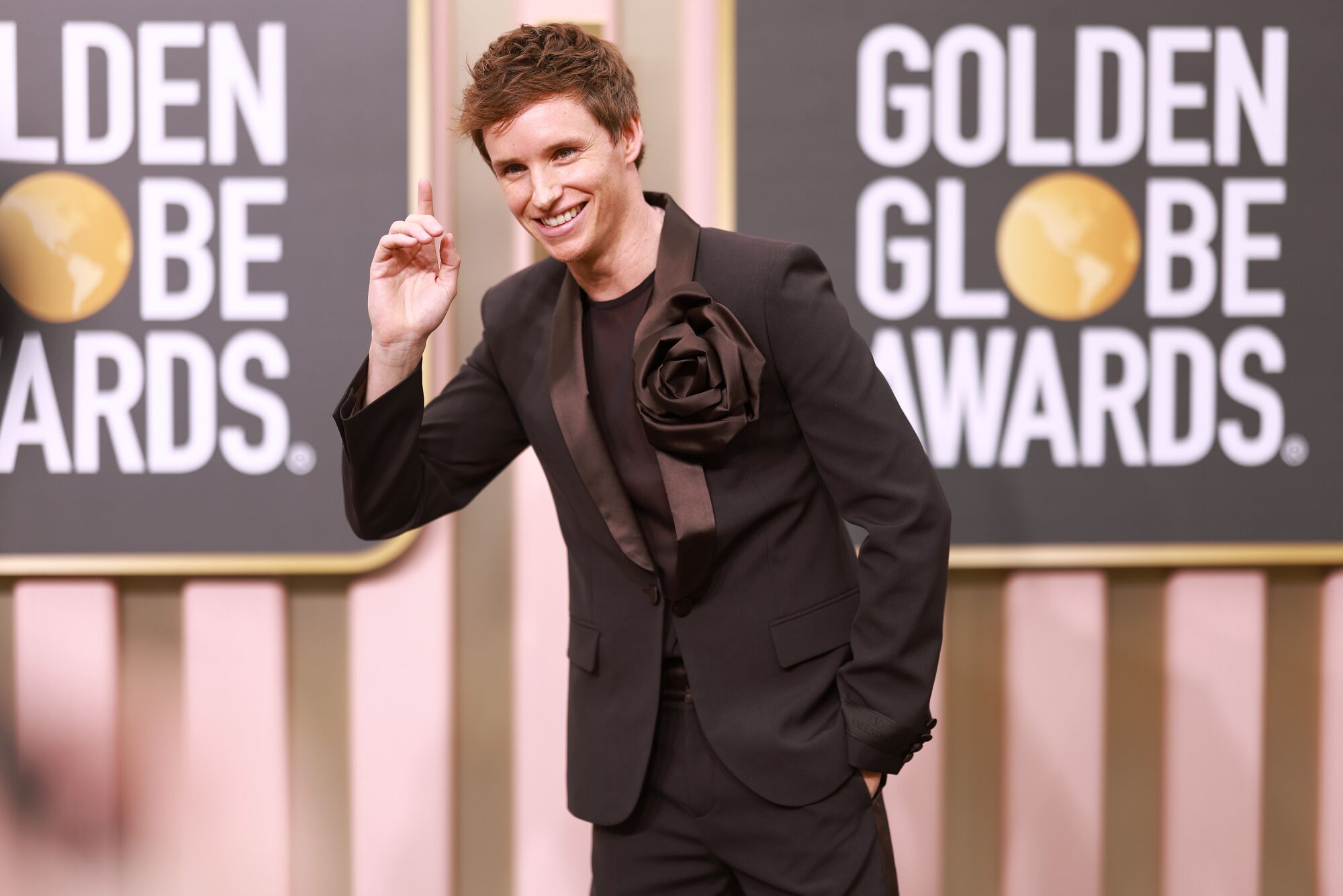 Eddie Redmayne dons a brown Valentino tux adorned with an oversized boutonnière.