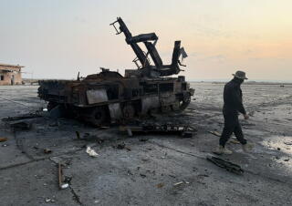 A man walks past wreckage on a tarmac