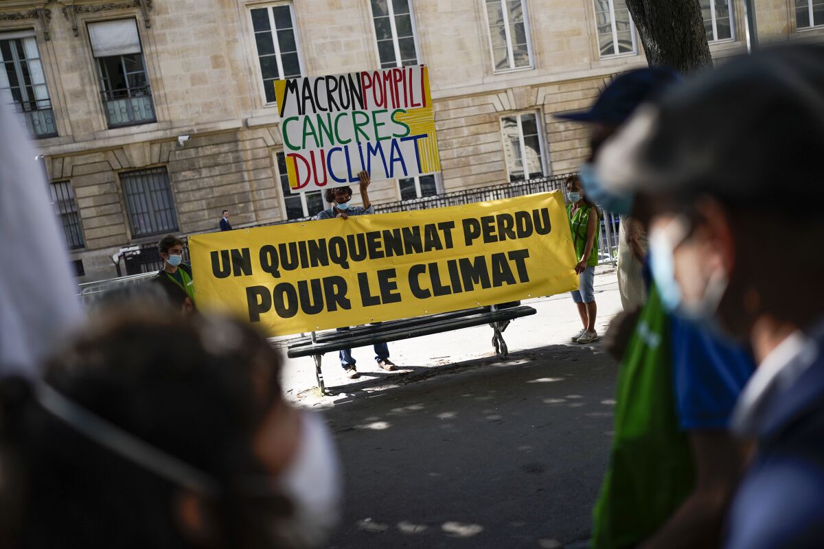 Climate activists hold a sign that reads "a five-year term lost for the climate" during a demonstration in Paris, Tuesday, July 20, 2021. France's parliament is holding a final vote Tuesday on a compromise climate bill that was meant to transform travel, housing and industry, but that environmental activists say doesn't go fast or far enough to slash French emissions. (AP Photo/Daniel Cole)
