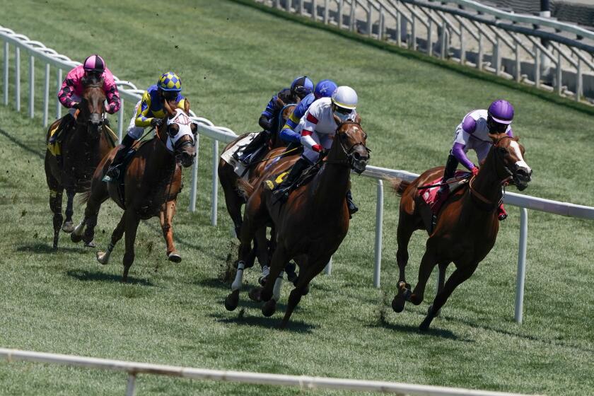 In this Friday, May 22, 2020 photo, jockeys wearing face masks ride in the third horse race.