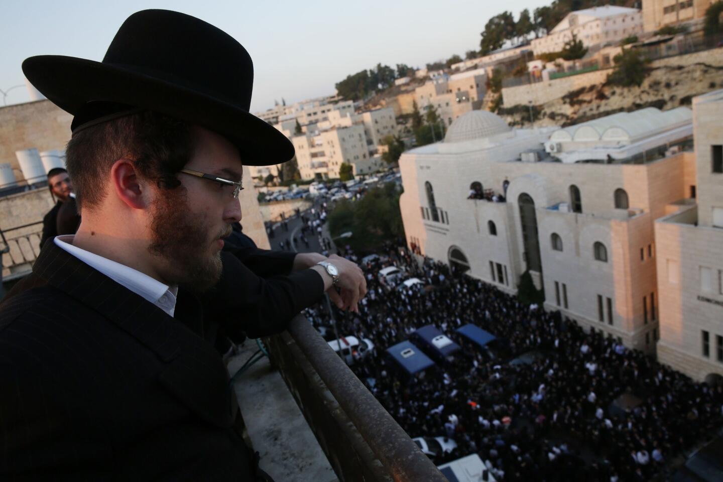 A man looks down at people mourning near the bodies of victims of an attack at a synagogue in Jerusalem.