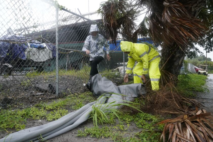 Robert and Donna Antognoni work to secure a tarp ahead of Hurricane Ian, Wednesday, Sept. 28, 2022, in Saint Petersburg, Fla. The U.S. National Hurricane Center says Ian's most damaging winds have begun hitting Florida's southwest coast as the storm approaches landfall. The hurricane's center neared Florida on Wednesday after rapidly intensifying overnight, gaining top winds of 155 mph. (AP Photo/Steve Helber)