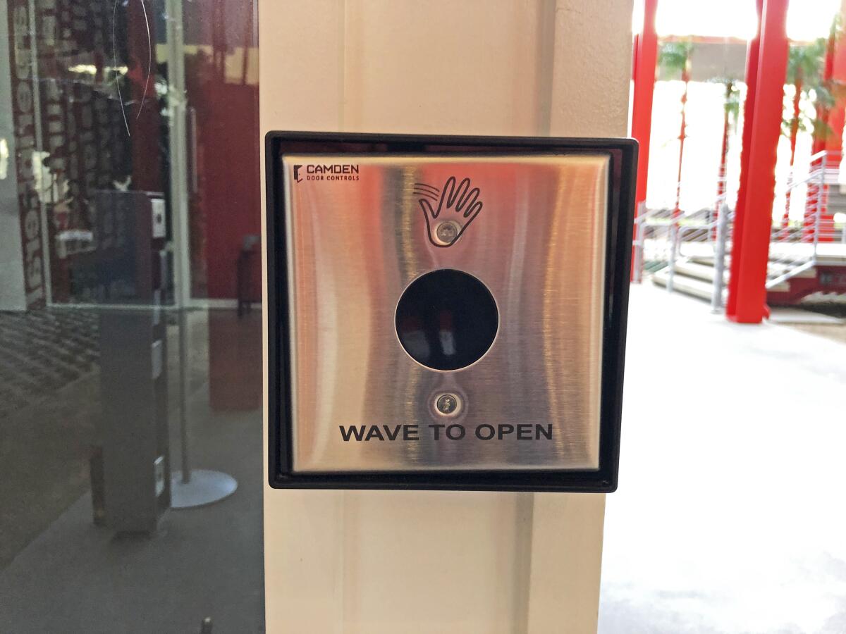 A metal box bears the icon of a hand and says "wave to open"