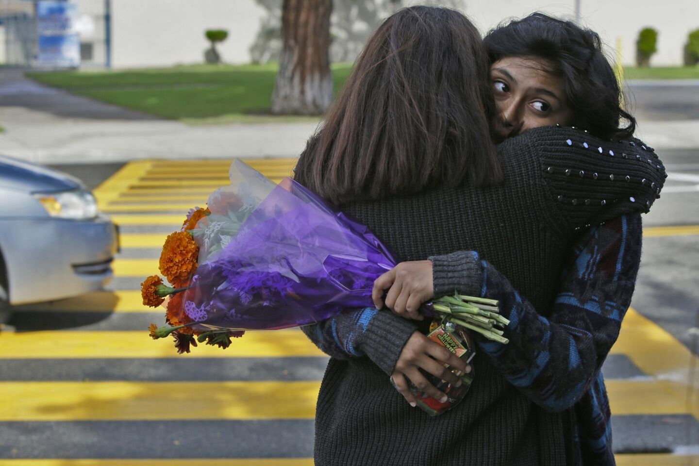 Jessica Beltran, left, and Isabel Rodriguez hug each other at the memorial for the three young trick-or-treaters killed by a hit-and-run driver in Santa Ana on Friday.