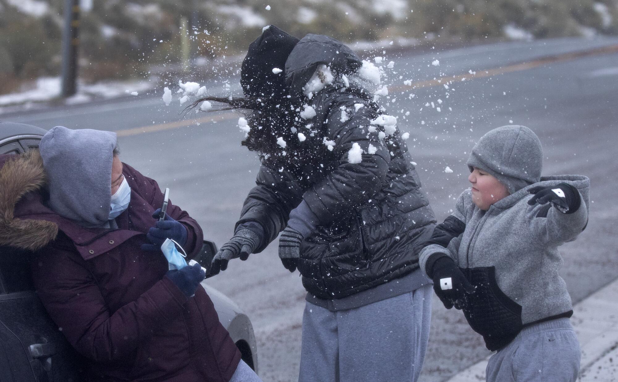 Sebastian Castillo, 8, right, hits his sister, Marilyn Castillo, with a snowball as mother Maria Martinez looks on
