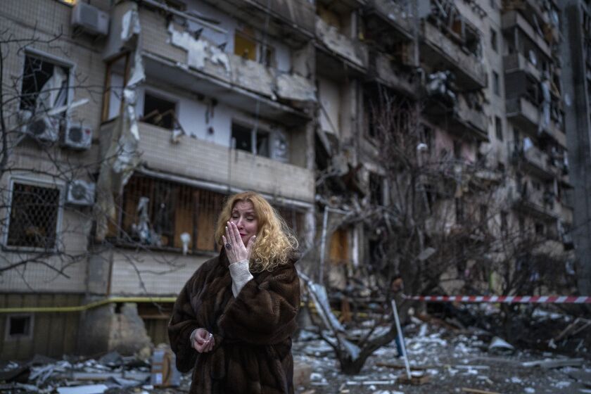 Natali Sevriukova reacts next to her house following a rocket attack 