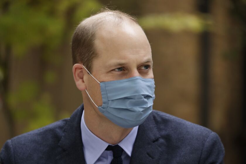 FILE - In this Oct. 20, 2020, file photo, wearing a face covering to curb the spread of coronavirus Britain's Prince William meets pharmacist Joyce Duah as he and his wife Kate the Duchess of Cambridge visit St. Bartholomew's Hospital in London, to mark the launch of the nationwide "Hold Still" community photography project. Prince William tested positive for the coronavirus, apparently around the same time as his father Prince Charles earlier this year, BBC reported. The report cited unidentified palace sources and The Sun newspaper, which said William kept his telephone and video engagements without revealing his diagnosis because he didn't want to worry anyone. (AP Photo/Matt Dunham, Pool, File)
