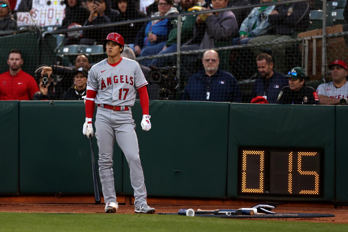 Angels star Shohei Ohtani stands in the on-deck circle next to the pitch clock.