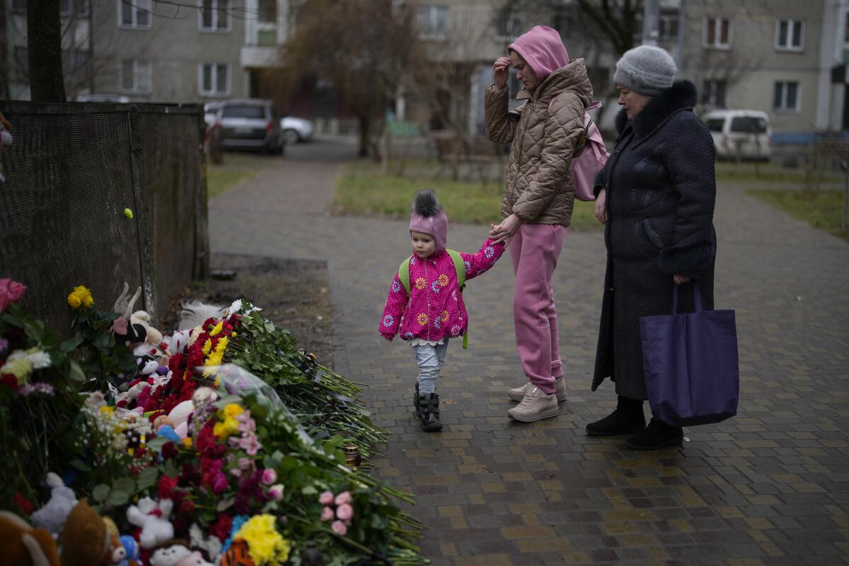 People stopping by makeshift floral memorial for victims of helicopter crash in Ukraine