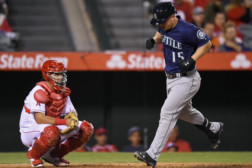 Seattle Mariners' Kyle Seager, right, scores after hitting a solo home run as Angels catcher Juan Graterol watches during the fifth inning on Wednesday.