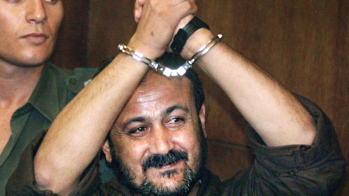 Jailed Palestinian uprising leader Marwan Barghouti raises his handcuffed hands as he enters the courtroom for the opening day of his trial at Tel Aviv's District Court, in this photo taken Aug. 14, 2002.