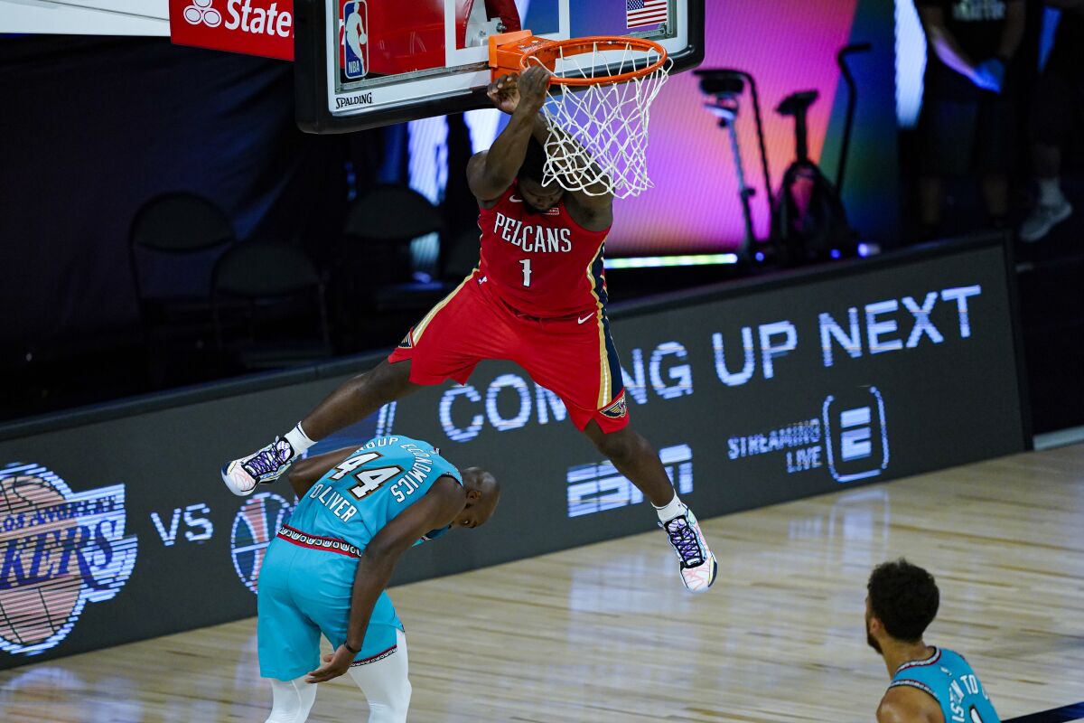 New Orleans Pelicans' Zion Williamson (1) comes down after a dunk over Memphis Grizzlies' Anthony Tolliver (44) during the first half of an NBA basketball game Monday, Aug. 3, 2020 in Lake Buena Vista, Fla. (AP Photo/Ashley Landis, Pool)