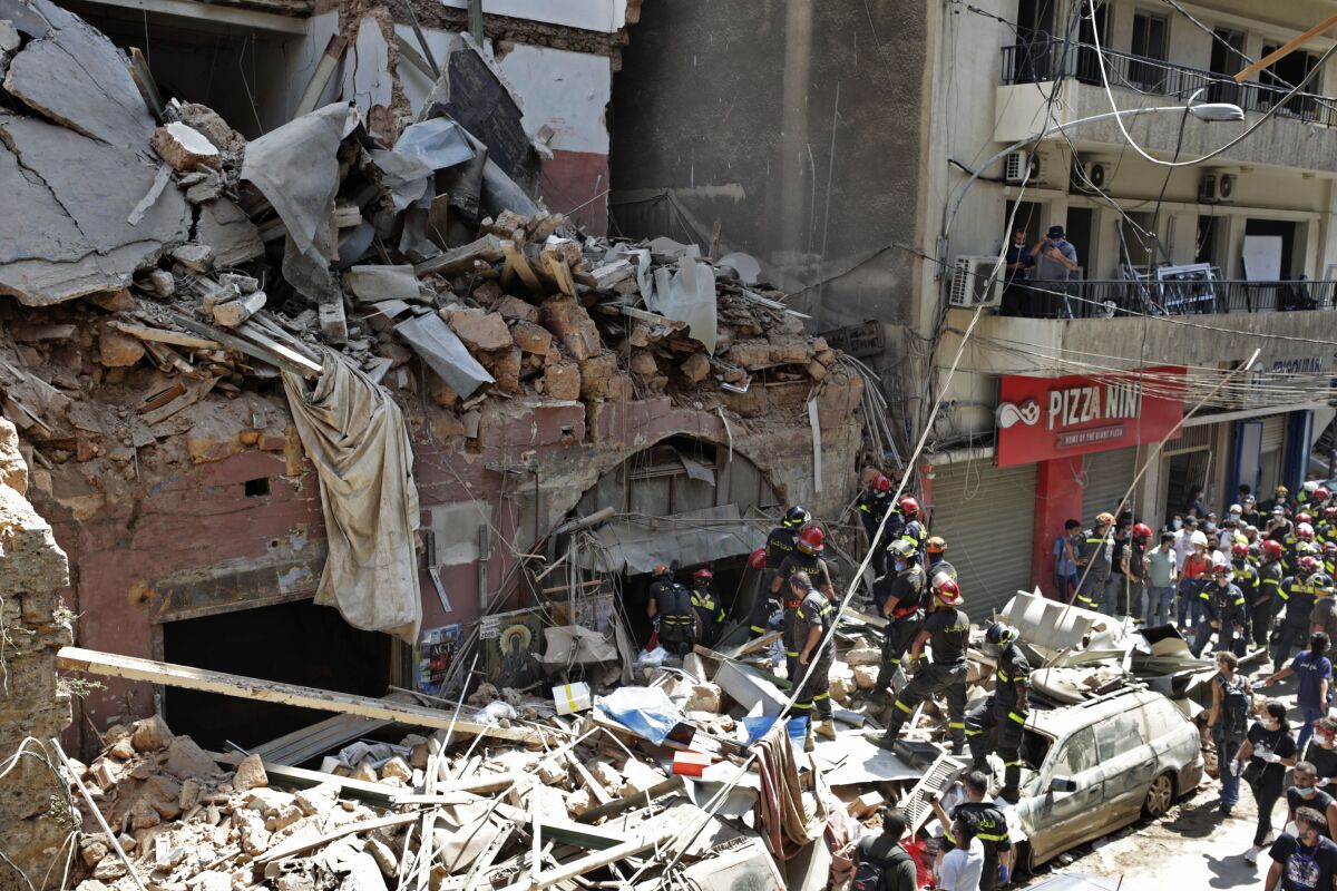 French and Lebanese firemen search in the rubble of a building after the Tuesday explosion at the seaport of Beirut, in Beirut, Lebanon, Thursday, Aug. 6, 2020. Lebanese officials targeted in the investigation of the massive blast that tore through Beirut sought to shift blame for the presence of explosives at the city's port, and the visiting French president warned that without serious reforms the country would "continue to sink." (AP Photo/Hassan Ammar)