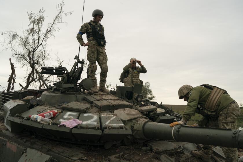Ukrainian servicemen stand atop a destroyed Russian tank in a retaken area near the border with Russia in Kharkiv region, Ukraine, Saturday, Sept. 17, 2022. (AP Photo/Leo Correa)