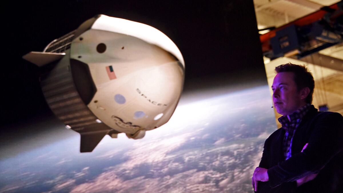 SpaceX CEO Elon Musk watches a video animation of SpaceX's Dragon V2 spacecraft at a news conference to introduce the manned space capsule in Hawthorne in 2014.