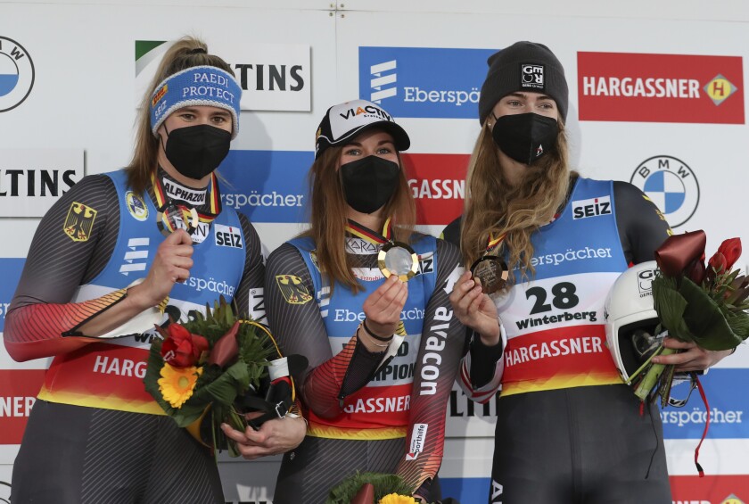 From left, runner-up Natalie Geisenberger, winner Julia Taubitz, both from Germany and third-placed Madeleine Egle from Austria stand on the podium after the women's single-seater competition of the Luge World Cup in Winterberg, Germany, Sunday, Jan. 2, 2022. (Friso Gentsch/dpa via AP)