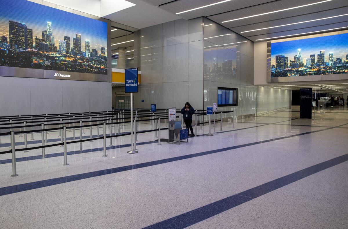 A Los Angeles International Airport worker stands near an empty TSA line in Terminal 7 on Saturday. 