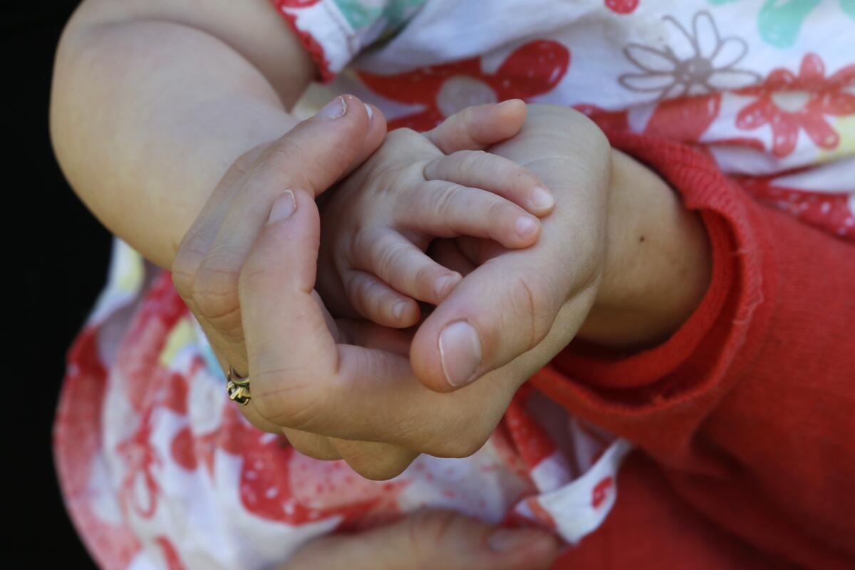 An adult holds a child's hand