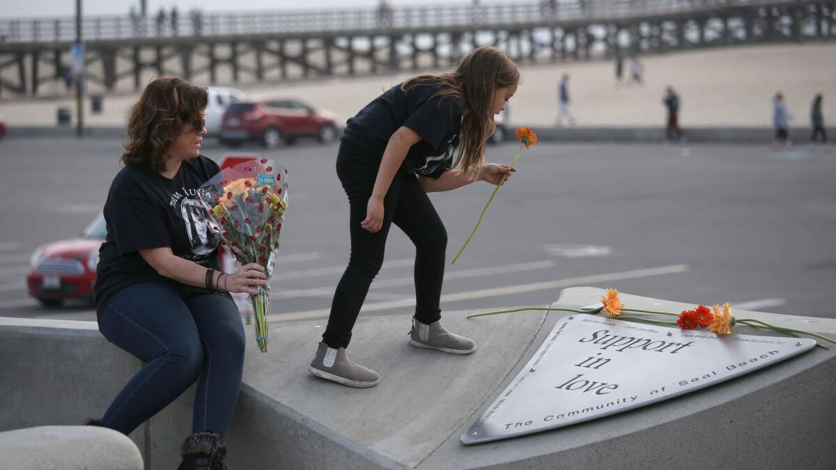 Christina Stretz, left, and her daughter Anabella Stretz, 9, lay flowers on the memorial for shooting victims at Eisenhower Park.