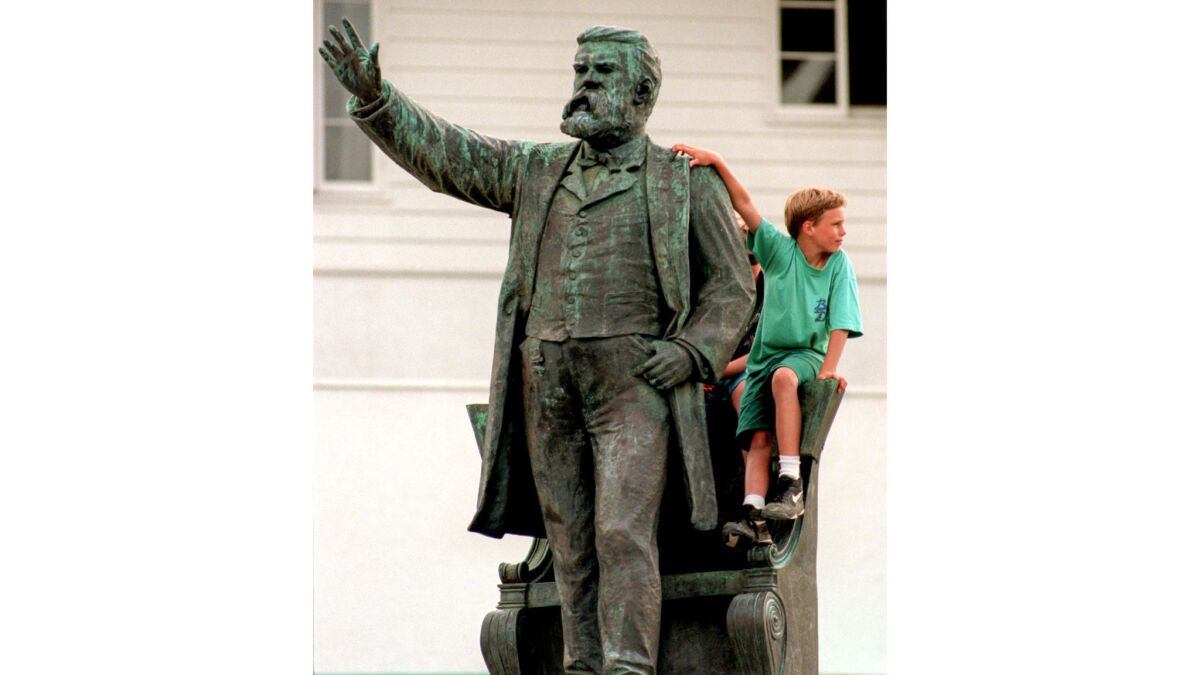 A boy sits on a statue of former Sen. Stephen White.