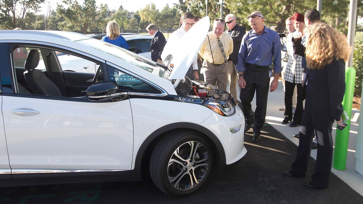 Newport Beach officials look at an electric-powered vehicle Tuesday at a new charging station at the Newport Coast Community Center.