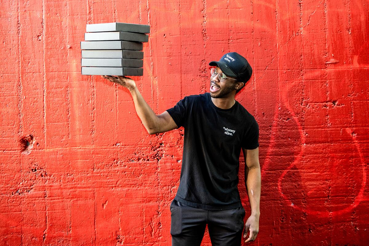 Kashka Hopkinson, owner of Stoney Slice, holding his custom black pizza boxes in Downtown Los Angeles.