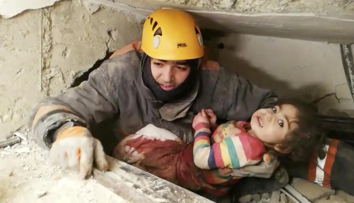 An image taken from video shows a rescuer pulling out a girl from the rubble of a collapsed building in Elazig, Turkey, on Saturday.