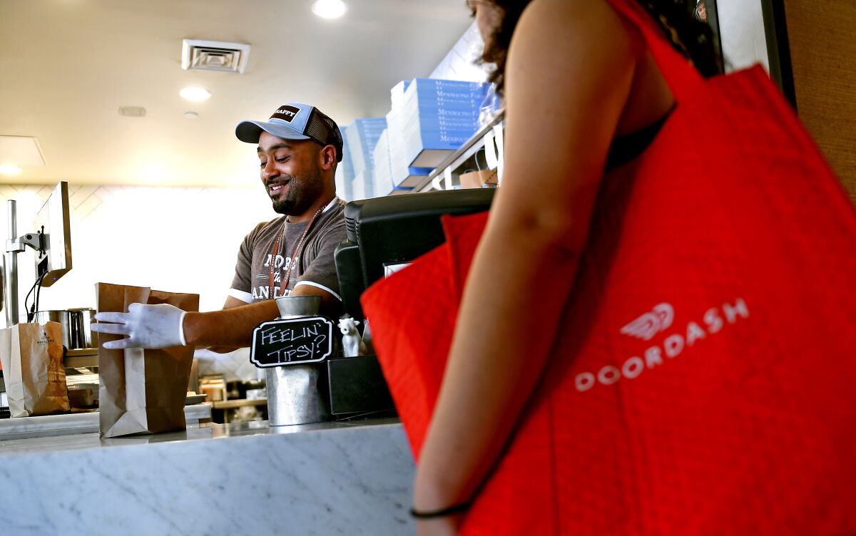 A Mendocino Farms employee packages food for a DoorDash delivery worker