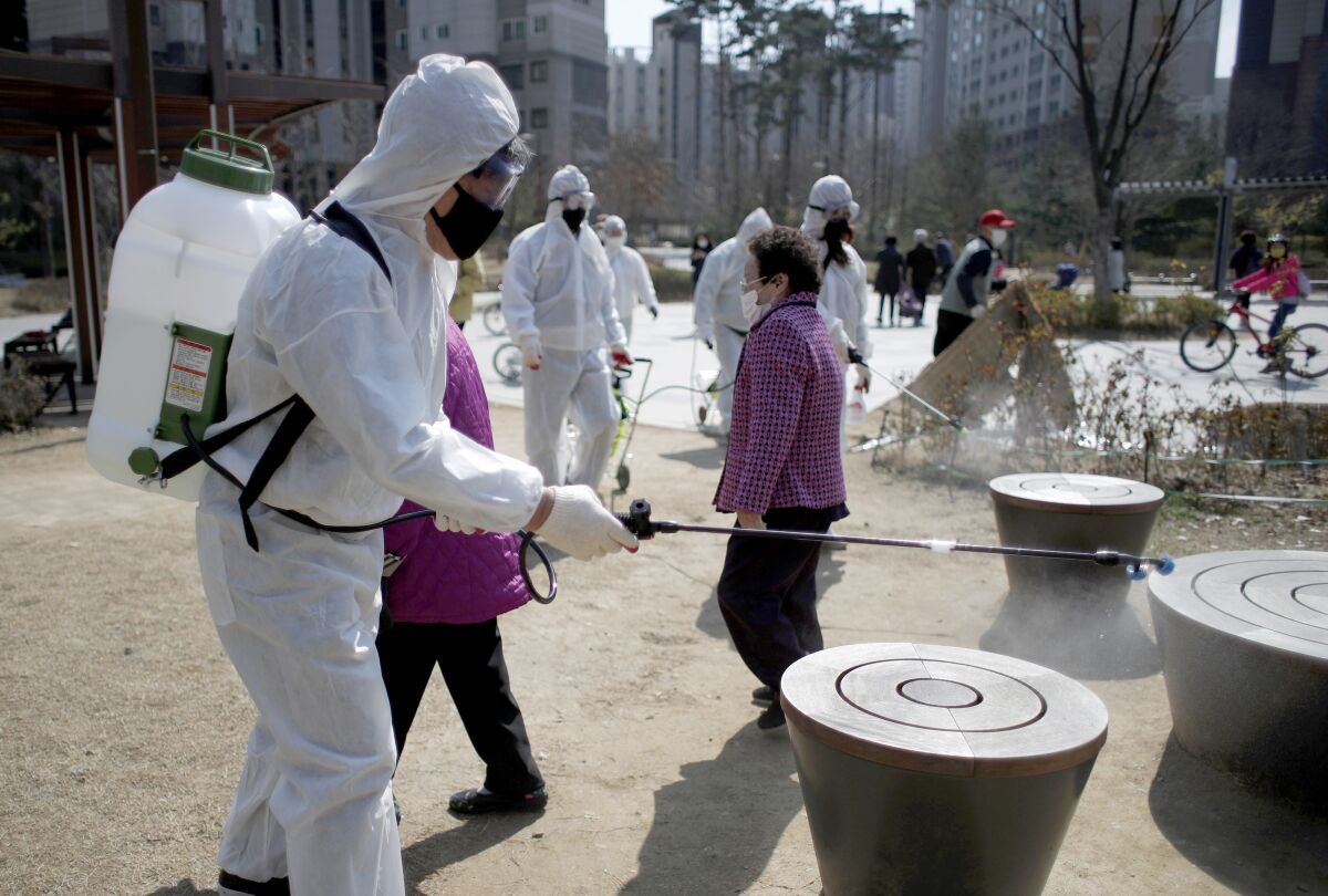 Members of a local residents group wear protective gear as they disinfect a local park as a precaution against the novel coronavirus in Seoul, South Korea.