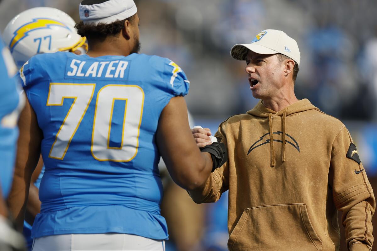 Chargers coach Brandon Staley greets offensive lineman Rashawn Slater during warmups.
