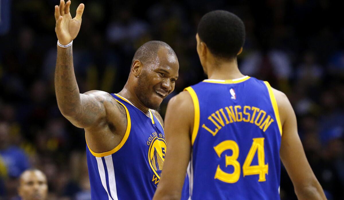 Warriors forward Marreese Speights (5) celebrates with teammate Shaun Livingston (34) after drawing a foul against the Thunder in the third quarter on Sunday.