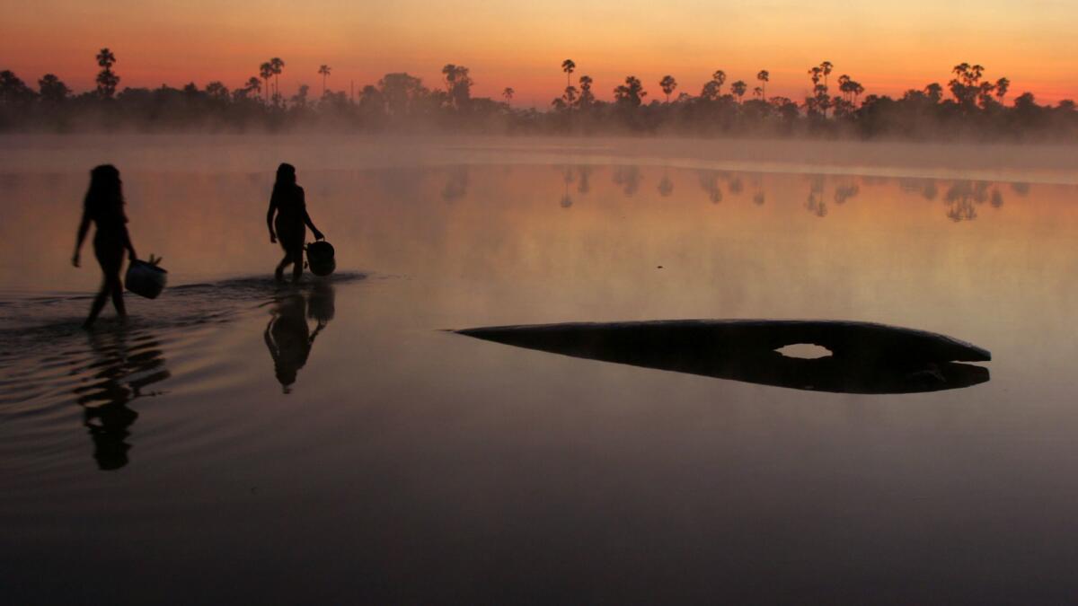 Indigenous women collect water from Lake Ipatse in the village of Kuikuro in the Amazon. The watchdog group Global Witness said indigenous people, particularly in the Amazon, have been killed in confrontations with ranchers, loggers, miners and poachers.