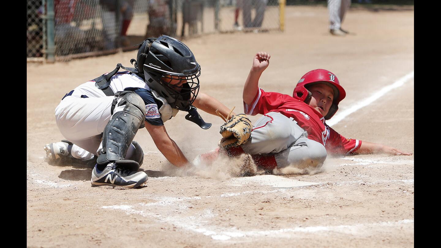 Newport Harbor Baseball Assn. catcher Parker Shea saves a run with this tag on Tustin's James Fuji during the second inning in the PONY Mustang 9-and-under Section tournament at A.G. Currie Middle School in Tustin on Saturday, June 30.