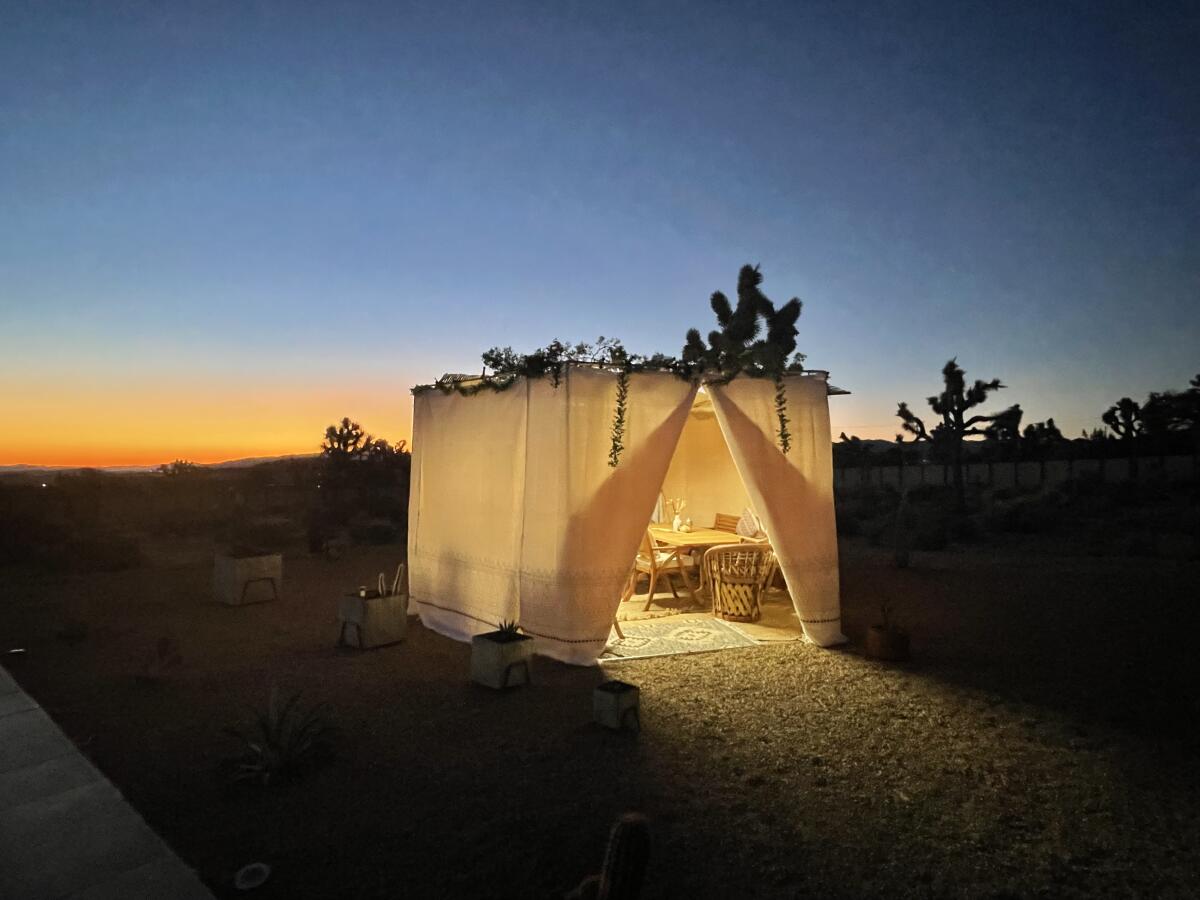 The covered sukkah of artist Bob Aronson and Lisa Schyck glows with an orange Yucca Valley sunset as its backdrop.