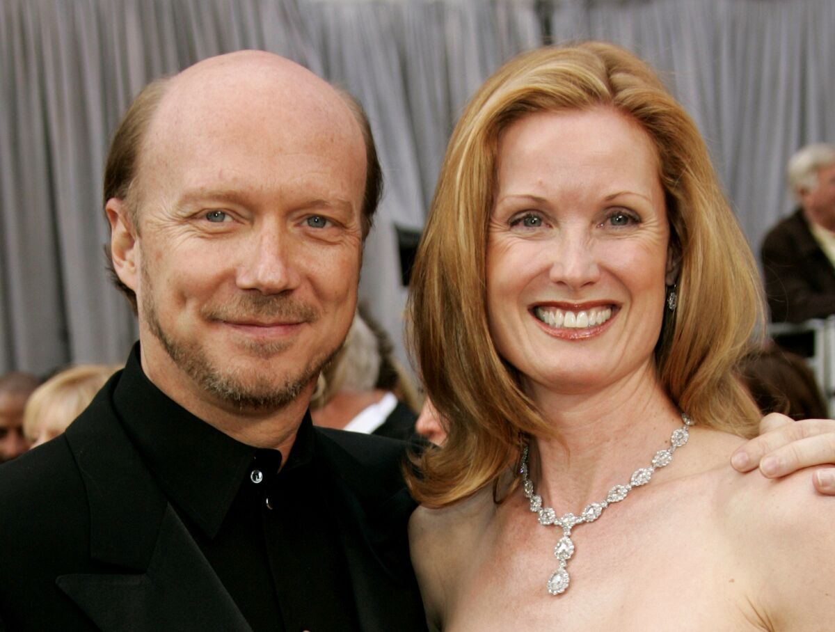 A smiling man has his arm around a smiling woman as they arrive at an awards show