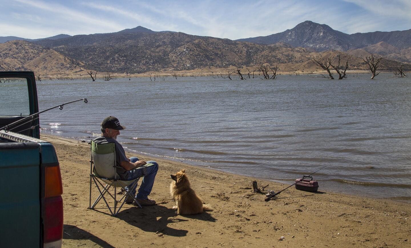 Dale Baker, with his dog Sarah, fishes along the shore of receding Lake Isabella.