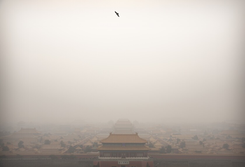FILE - In this Jan. 18, 2020, file photo, a bird flies over the Forbidden City on a day with high levels of air pollution in Beijing. China's Premier Li Keqiang announced that the country would target a reduction of 18% in carbon intensity over the course of the next five years as part of the meeting of the ceremonial legislature which kicked off its annual meeting Friday, March 5, 2021. (AP Photo/Mark Schiefelbein, File)
