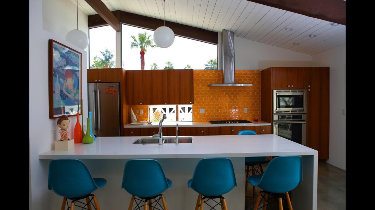 The enclosed kitchen was demolished in favor of a new open space that merges seamlessly with the dining and living rooms and outdoors. Shiell chose quartz countertops, walnut cabinets and Modwalls ceramic tile in a bright orange vintage hue to give the room a timeless modern quality.