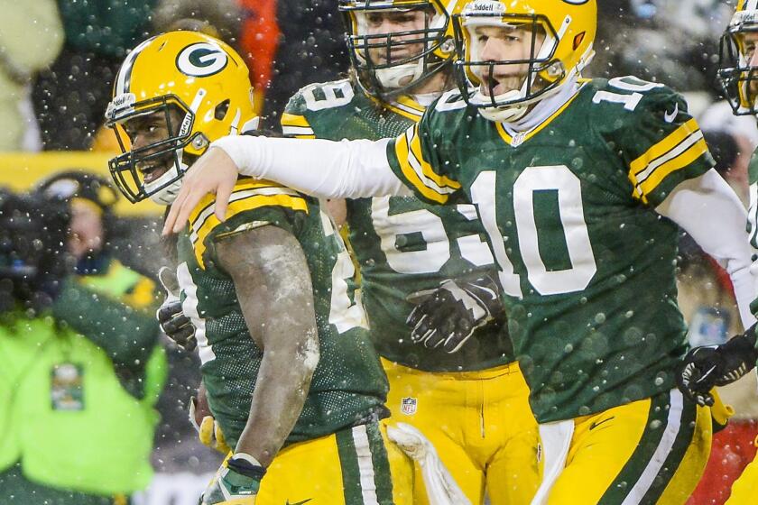 Green Bay Packers offensive player Eddie Lacy (L) celebrates scoring a touchdown with Green Bay Packers quarterback Matt Flynn (R) and Green Bay Packers offensive player David Bakhtiari (C) as snow falls in the first half of their NFL game at Lambeau Field in Green Bay, Wis.
