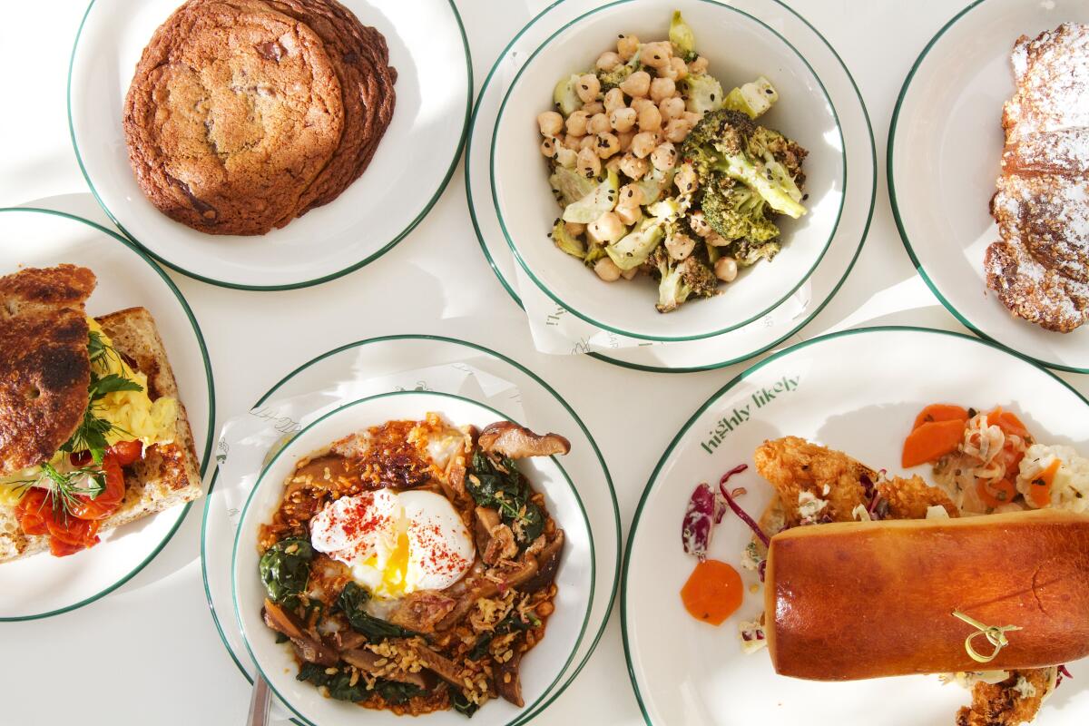 An overhead photo of dishes from all-day cafe Highly Likely on a white tabletop: fried fish sandwich, rice bowl and more.